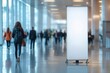 © Yuliya - Roll up, blank banner in the lobby of a business center. White sheet of advertising inside the premises with blurred people in the background. Roll up mockup.