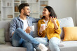 © Home-stock - Loving hindu spouses drinking coffee and chatting while sitting on sofa at home, enjoying spending time together on weekend. Happy romantic relationship