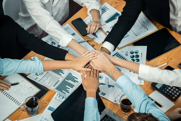 Multiracial business people make synergy hand stack together in meeting room as cooperation or team building for corporate employee in workplace. Top view. Meticulous