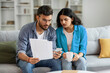 © Home-stock - indian couple reading papers and calculating spends,planning budget together,using cellphone
