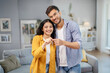 © Home-stock - Satisfied young indian spouses show keys at own flat in living room, enjoy moving, buying new home, renting house together, copy space