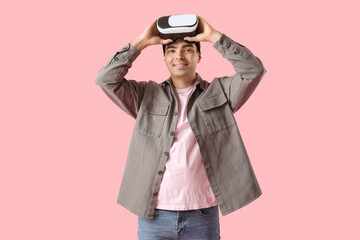 Wall Mural - Happy young man with VR glasses on pink background