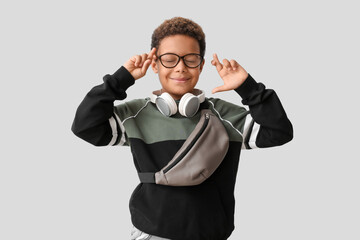 Poster - Little African-American boy with headphones making wish on white background