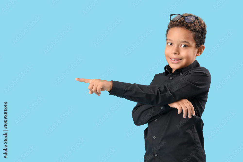 Little African-American boy pointing at something on blue background