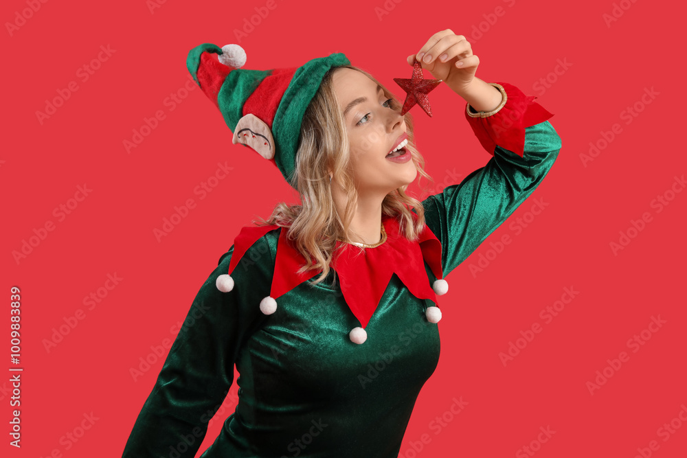 Funny young woman dressed as elf with Christmas decor on red background