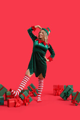 Sticker - Beautiful young woman dressed as elf with Christmas gifts on red background