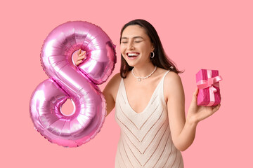 Canvas Print - Happy young woman with pink air balloon in shape of figure 8 and gift box on color background. International Women's Day