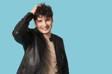 Wall Mural - Handsome young man in stylish leather jacket on blue background