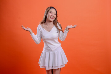 beautiful indonesia woman gesture white top standing happy candid both palms up isolated orange background. for fashion concept, advertising, promotion, commercial