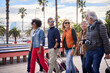 © CarlosBarquero - Side view of group of happy mature friends walking with their luggage on street European city looking at each other. Diverse middle-aged people enjoy their leisure time on holidays. Copy space
