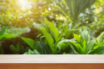 Empty wooden table on blurred green leaf background, with natural light.