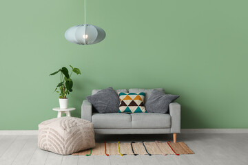 Poster - Stylish living room with grey sofa, houseplant, pouf and modern hanging lamp