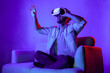 © Summit Art Creations - Man looking and touch to explore in simulated metaverse by using VR glasses. Happy person with headset sitting at sofa while enter in virtual world by using futuristic technology equipment. Deviation.