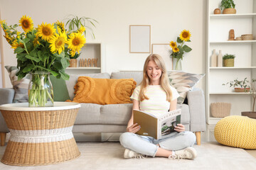 Poster - Beautiful young happy woman with bouquets of sunflowers reading magazine at home