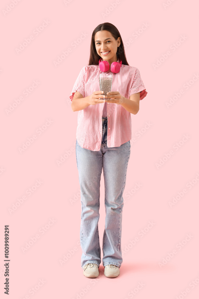 Young woman with chia seed water on pink background