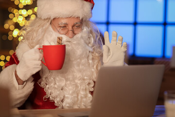 Canvas Print - Santa Claus with cocoa video chatting at home on Christmas eve, closeup