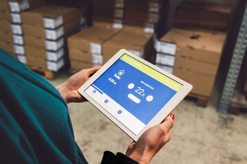 The young female owner and the man in the warehouse check the temperature, energy consumption and lights on a tablet.