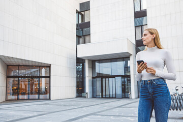 Young caucasian woman portrait on the street in dusk with digital tablet. Walking in business district.