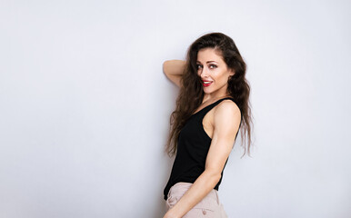 Wall Mural - Happy toothy smiling make-up woman with red lipstick, long brown hair looking happy in black top on empty copy space studio blue background. Portrait front view