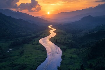 A scenic view of a winding river flowing through a lush green valley with majestic mountains in the background as the sun sets.