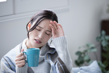 Wall Mural - Close-up of a woman who is sick and unwell at home with a cold, fever headache or migraine 