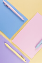 Wall Mural - Top view of pink, purple and blue notebooks on yellow background. Pink, yellow and blue pens, school, office wallpaper. Flat lay, copy space.