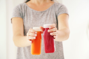 Canvas Print - Woman holding in hands plastic bottles with red and orange smoothie