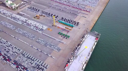 Wall Mural - A newly produced car carrier is docked at the port and is loading cars onto the ship to be shipped to countries around the world for sale.