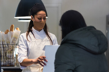 Female baker talking to customer in bakery