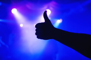 man's hand shows gesture thumbs up on a blurry background