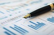 © ZpongXED - A close-up of a fountain pen resting on a financial report filled with charts and graphs, representing analysis and business planning.