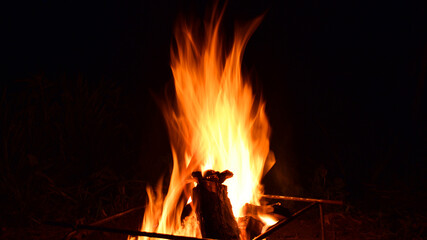 firewood burns, fire coals at night. Red hot coals glowing on a dying campfire pit. Orange glow from the coals at the stake at night. flames on a black background