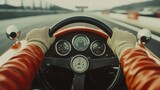 Racer hands wearing cream-colored gloves gripping steering wheel of vintage race car, speeding up down the track