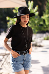 Wall Mural - Beautiful young woman in stylish black hat on city street