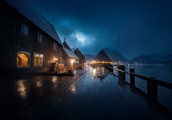 Poster - Night view of a wooden pier with water in the distance and buildings in the background with rain falling.