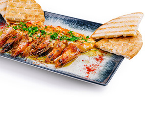 Grilled shrimps with garlic, olive oil, parsley and pita bread lying on rectangular plate