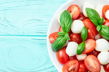 Basil leaves , cherry tomatoes and mozzarella cheese . In bowl food photography