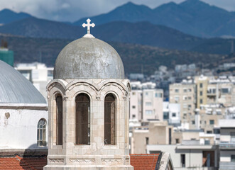 Stone bell tower of Holy Trinity of Agia Zoni church with cross dominating skyline of Limassol city, Cyprus