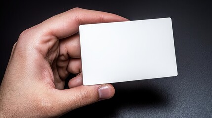 A blank card held in a hand, perfect for personalizing or branding purposes in a minimalist style on a dark background.