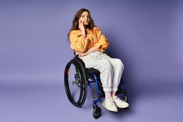 A young woman in a wheelchair sits with a relaxed and confident pose in front of a studio backdrop.