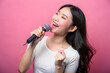 © KingKongThePitbull - Asian young holding microphone singing song and Enjoying. isolated on pink color background
