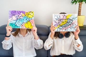 Teenage girls holding neurographic drawings, faces covered. Abstract neurographic drawing with markers and colored pencils. Colorful neurography