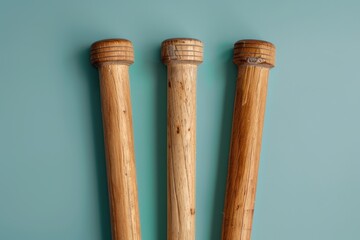 Three wooden baseball bats arranged on a teal background