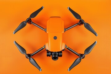 Top view of an orange drone with four propellers and a camera on a bright orange background