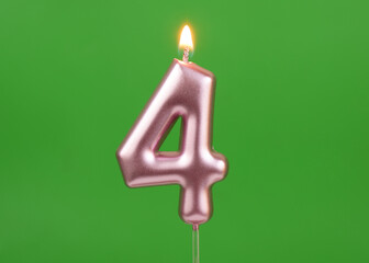 Burning pink birthday candle on green background, number 4