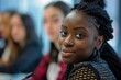 © CojanAI - Young black businesswoman in focus during a office meeting with other employees