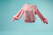© VICHIZH - Pink fluffy sweater floating against a blue background Stylish and cozy, perfect for autumn and winter fashion A modern and playful concept for apparel