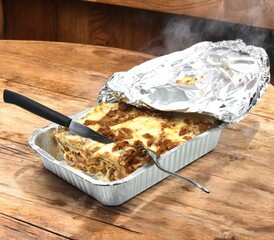 Steaming hot lasagna ready to be served on wooden table