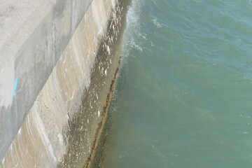 glancing down at edge of a concrete barrier wall and water