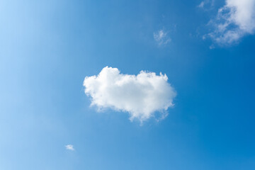 Fluffy cumulus clouds form a heart shape in the clear blue sky, a breathtaking natural phenomenon